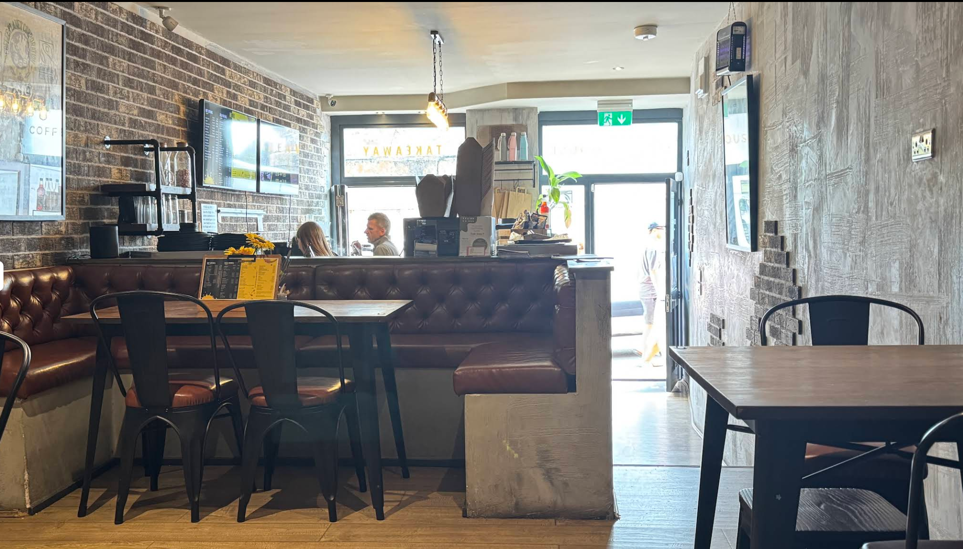 Interior seating area with brick walls and booths at Crafted Coffee House